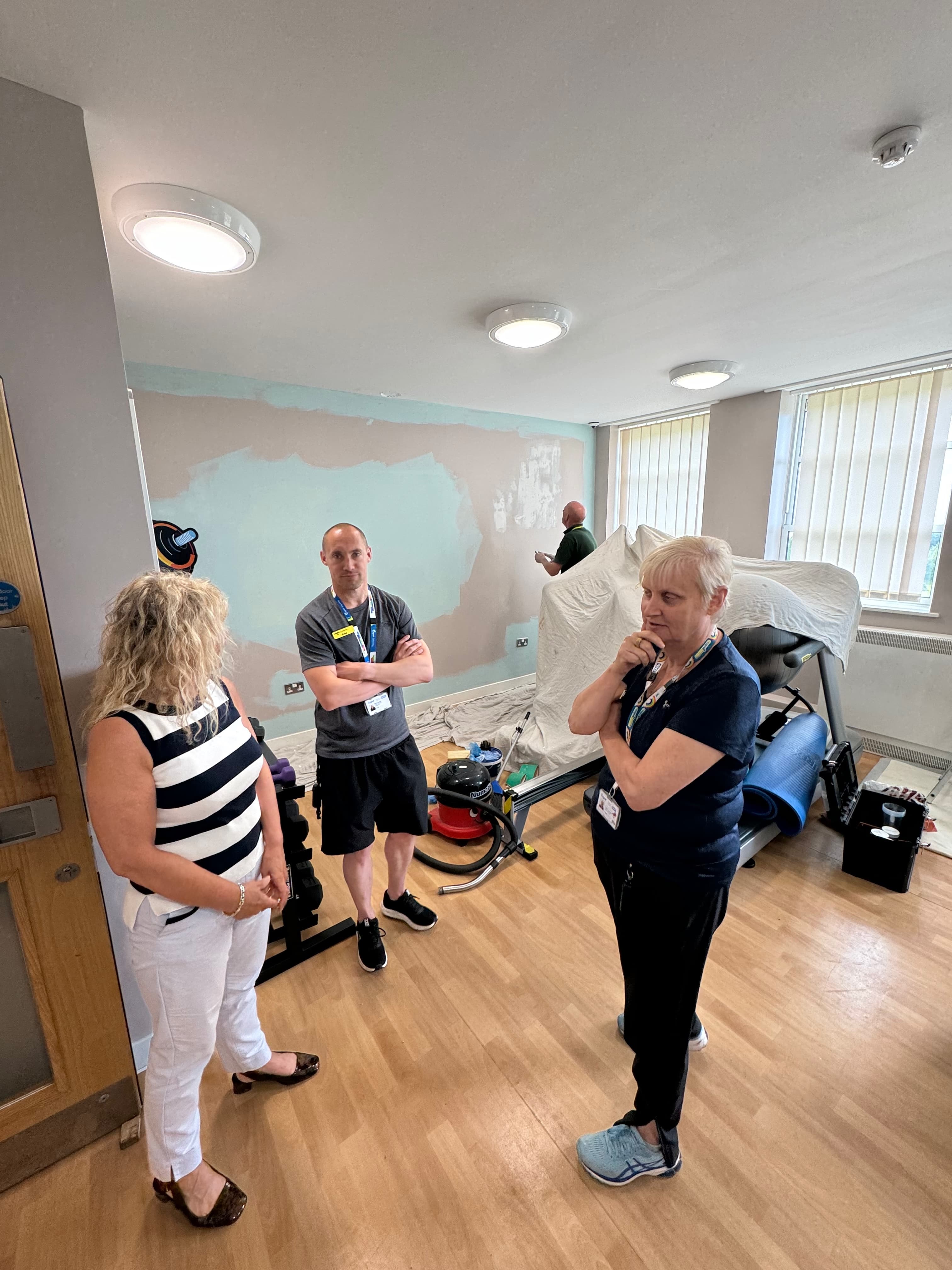 Three people discussing a room and its equipment during a visit.
